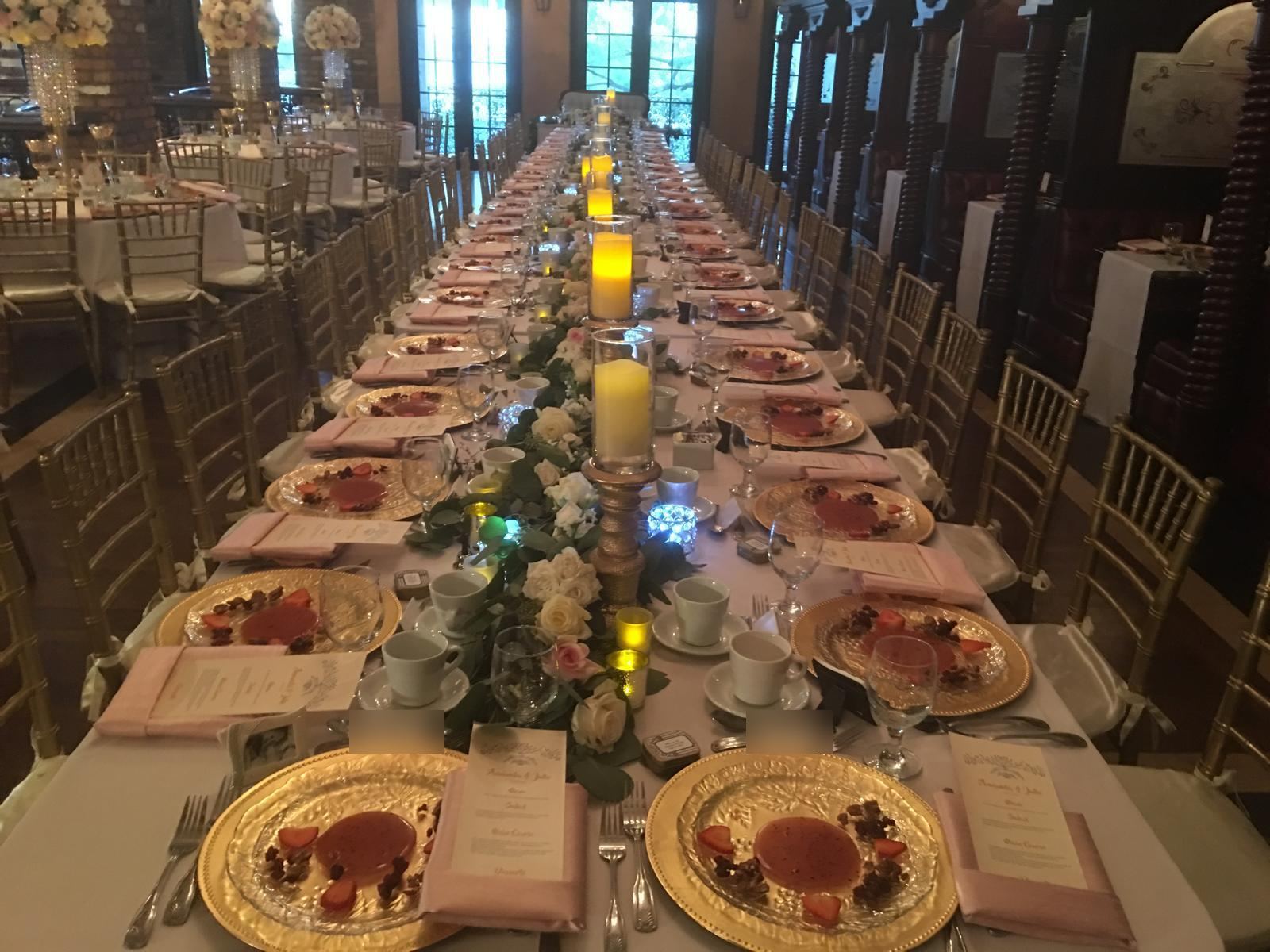 Candlelit ballroom wedding table with gold chargers and blush menus