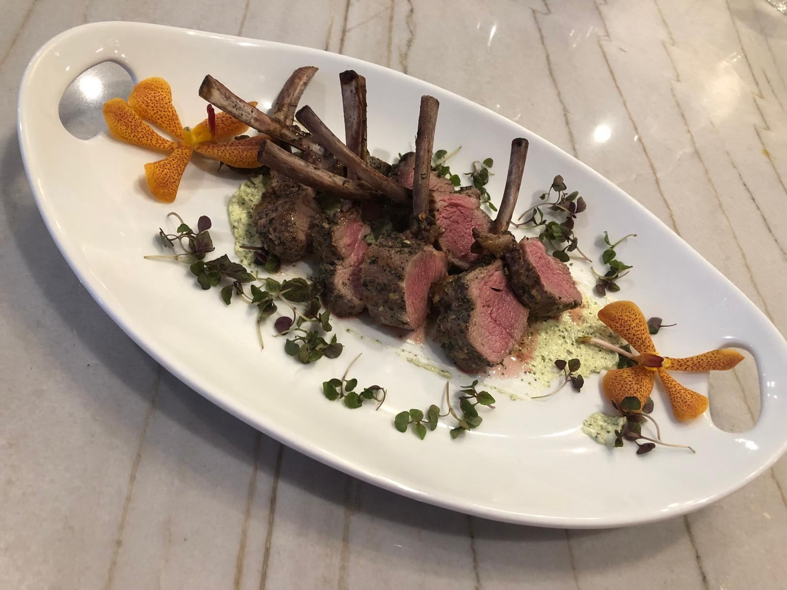 Herb-crusted lamb chops with orchids on a white platter